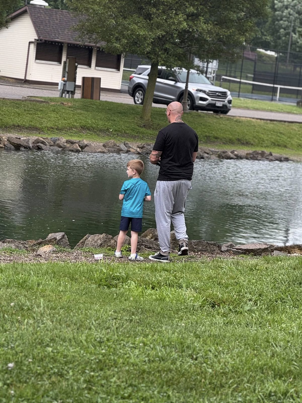 A dad fishing at the pond with his young son