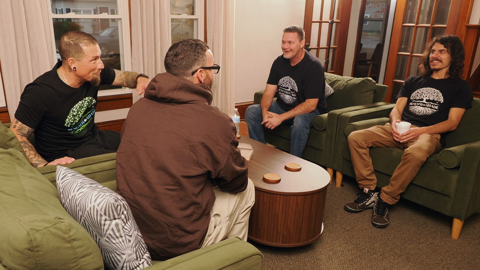 Men from Beneath the Shade in conversation around a coffee table at Jack's House of Hope